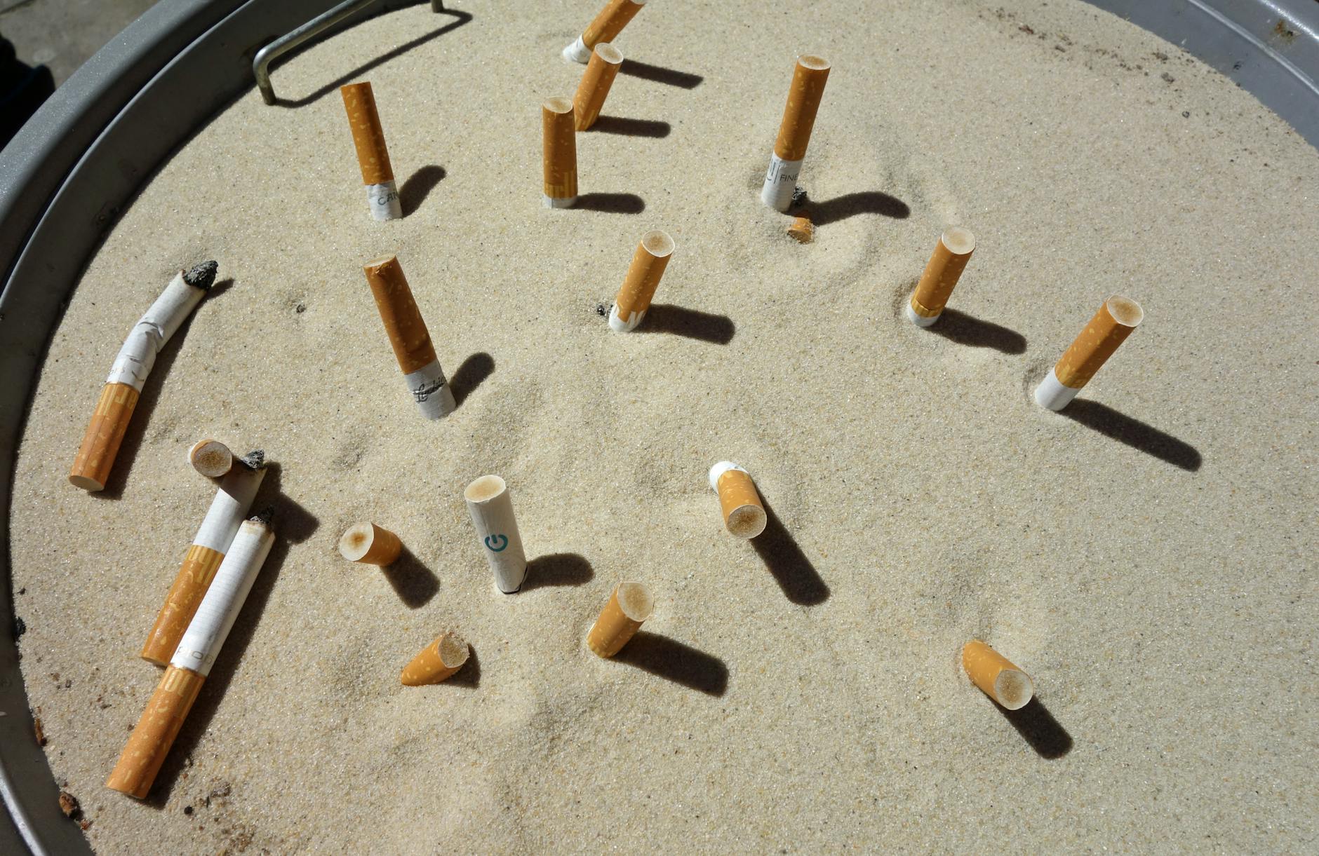 discarded cigarette butts on ashtray sand