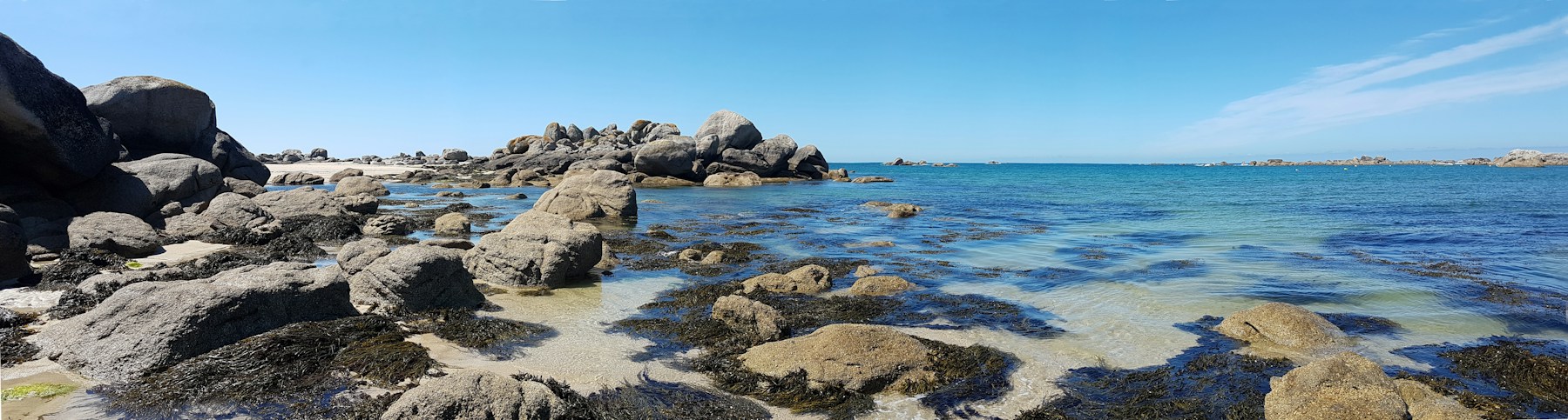Rochers et eau claire sur le littoral breton sous un ciel bleu. Photographie d’ambiance.